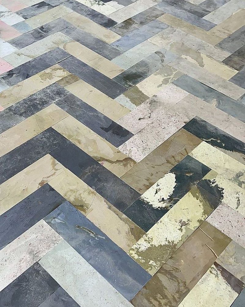 A herringbone floor of grey, cream, rust and olive strips.