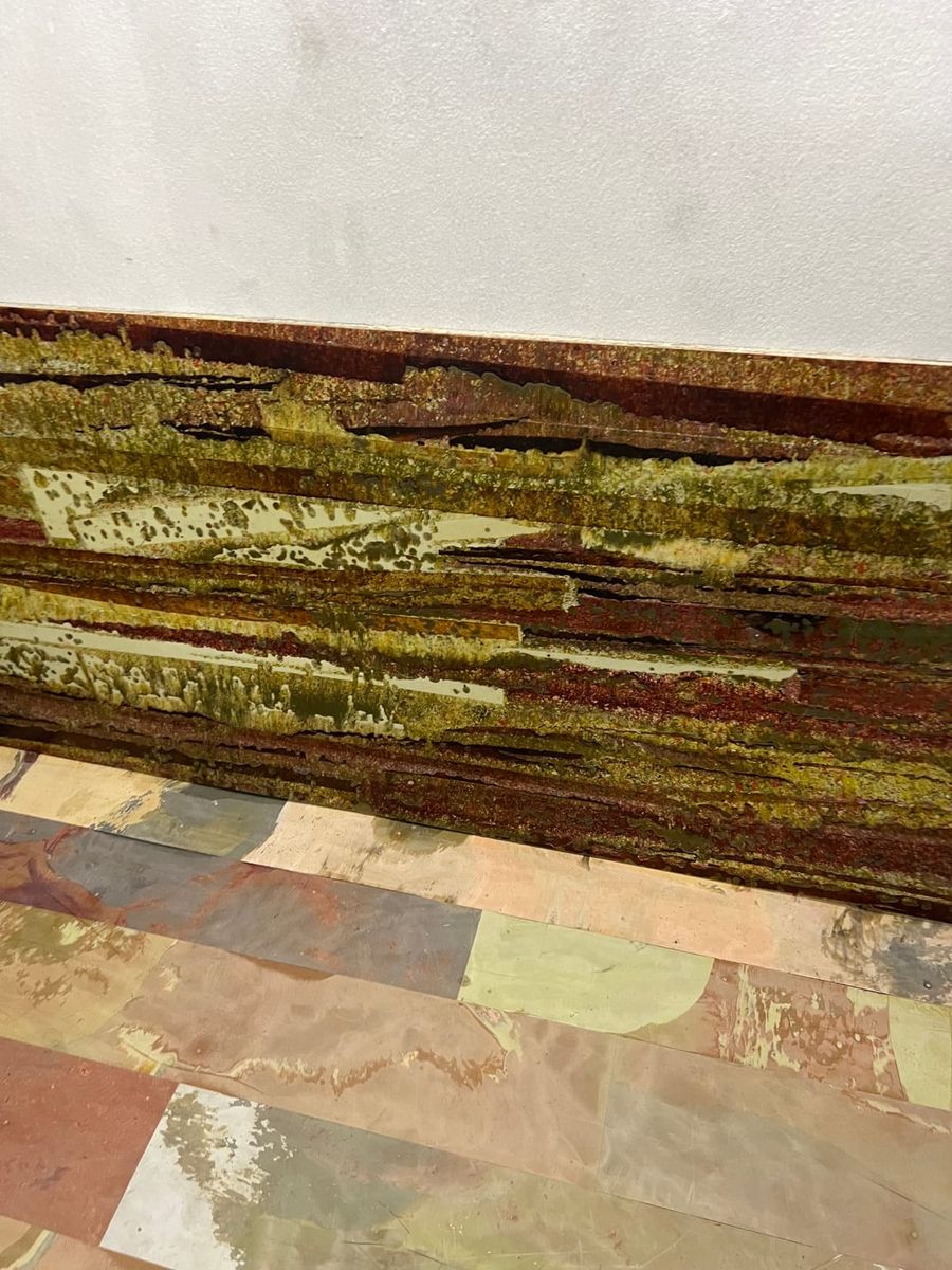 A close view of a layered yellow, brown and cream patterned wall panel above multicolour floor strips.